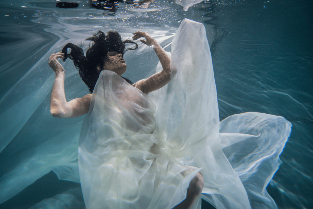 Mujer sumergida bajo el agua, vestido blanco, muejr disociacion de la realidad disociada