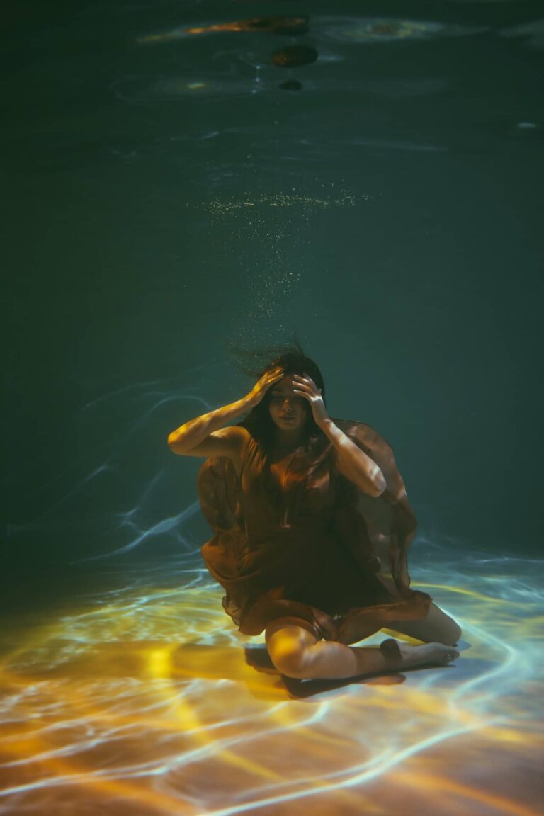 Mujer Joven sumergida bajo el agua, vestido marrón, mujer disociacion de la realidad disociada