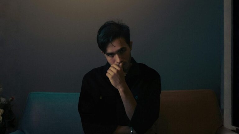 Hombre sentado con mirada suspicaz y calculadora, expresión característica del narcisista maligno que evalúa su entorno buscando ventaja